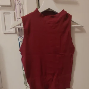 Mörkrött linne - Rött ribbad linne med hög krage. Inte använd. 