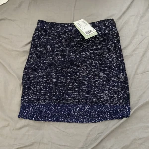 Glittrig minikjol - Glittrig minikjol i en marinblå färg, passar perfekt till fest. Helt oanvänd