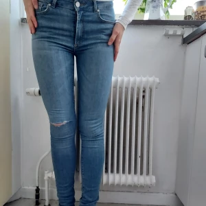 Ljusa Ripped Jeans  - Ljusblå jeans slitna på knät tight modell