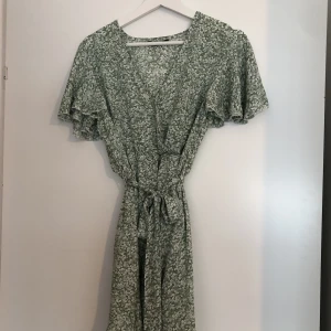 Blommig klänning - Jättefin blommig klänning. Använd en gång. Den ser mer ljusgrön ut i verkligheten än på bild