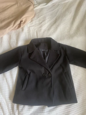 Svart kort kappa - Säljer denna jättefina svarta kort kappa. Vet inte vart den ursprungligen kommer från. Knappt använd och är i bra skick. Säljer pågrund av att jag köpt en ny