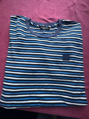 Acne T-shirt Strl M - Randig kortärmad T-shirt från Acne, strl M i 100% bomull. Perfekt att möta vårsolen i .