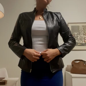 Figursydd skinnjacka - Vintage skinnjacka som är figursydd, går in i midjan. Snygg både öppen och stängd. Lite för liten för mig att stänga (strl 38) rekommenderar till strl 36 om du vill stänga.   Ursprungs pris: 900kr
