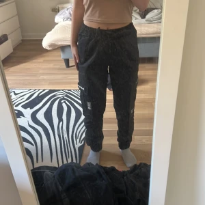 Cargobyxoe - Svarta blacksquad byxor. Fickor på sidorna av låren. Använd ett par gånger men i bra skick.