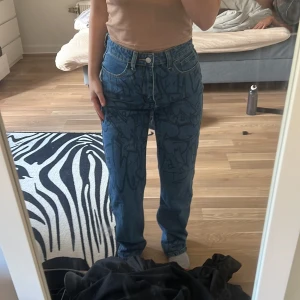Jeans med graffiti  - Jeans med graffiti mönster på övre delen av byxorna. Använt ett fåtal gånger så är i bra skick. Är storlek xs men passar som s. 