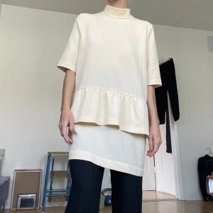 GANNI klänning  - Offwhite klänning från GANNI. Storlek L men liten i storlek och jag tycker den funkar även som oversize (jag på bilden är XS och 156cm lång). Även snygg med byxor under.  Har haft någon noppra men har fått bort det mesta med noppmaskinen. 