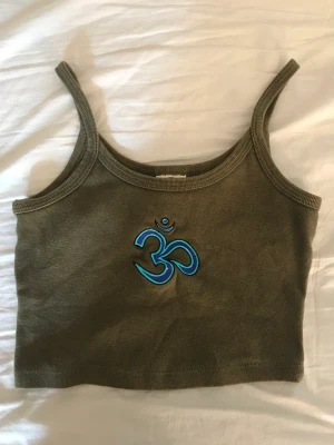 Grön croptopp - En jättefin grön croptop med blått tryck på. Bra skick och inga hål eller några konstigheter! Säljer den då den är lite för stor och inte min stil längre!