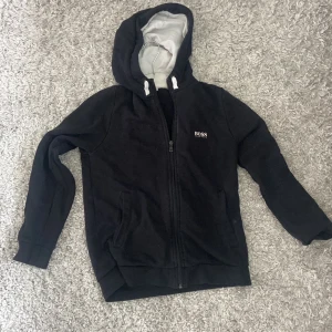 Hugo boss cardigan  - Säljer en Hugo boss tröja då den inte kommit till användning på 1,5 år , köpt i Göteborg på nk på barnavdelningen . Den är väldigt tvättad men trycket är hyfsat bra fof , nypris 1000 , mitt pris 400🥰 kan diskuteras 