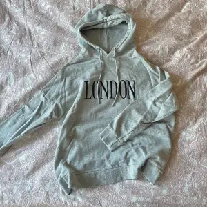 Grå hoodie med texten ”London”. 