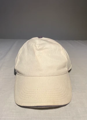 Baseballkeps  - Beige keps med mörkblåa detaljer.  