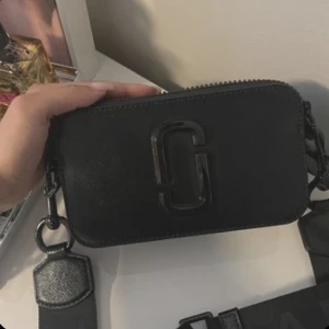Marc Jacobs väska - Säljer denna fina Marc Jacobs väskan som är helt ny in princip. Väskan är i helt nytt skick. Man kan också justera banden så att den blir kortare/längre. Nypris: 4400 kr. Pris kan diskuteras. Den är äkta o finns äktehetsbevis. kontakta för mer bilder🤍