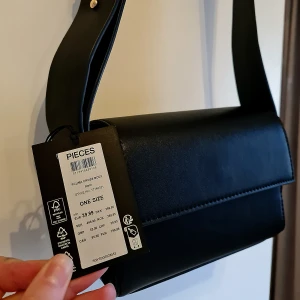 Helt ny handväska  - Helt ny handväska i fejkläder från Vera Moda. Tjockt band och justerbar med "knappar" i guld 