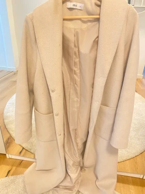 Beige kappa - Beige kappa från Ellos i storlek 36. Perfekt inför vintern! 
