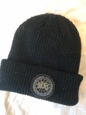 Canada Goose Mössa  - 100% Äkta med kvitto, prissänkning vid snabb affär. Kommer med original påse och så klart kvitto. använd få talgånger men inga hål eller sånt