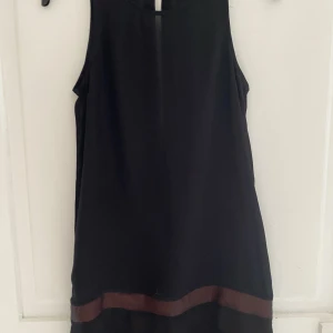 Klänning  - Klänning i nyskick med snygg öppen rygg. Strl XS men passar XS-S. Svart men orange kant nertill. 