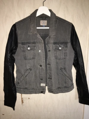 Grå oversize jeansjacka med PU läder ärmar, EMP storlek S - Grå oversize jeansjacka med PU läder ärmar Märke: EMP Storlek: S (oversize) Färg: grå och svart  Skick: använt gott skick