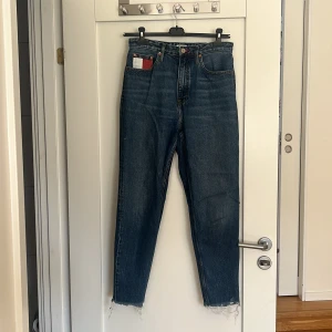 Tommy mom jeans - Säljer ett par väldigt fina Tommy jeans, tyvärr är dom för små för mig!  Storlek 28/32! Mom jeans! De ska sluta precis där skon börjar.  Använda ganska mycket men de är i fint skick ändå. 