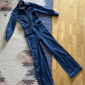 70’s denim jumpsuit - Vintage denim jumpsuit i UK strl 10. Skulle uppskatta att den passar en strl 32-34. Den mäter 35cm tvärs över midjan och 86cm innerbenslängd. Hör gärna av dig med frågor vid intresse! 