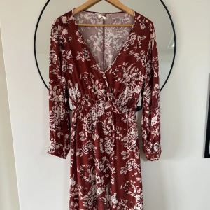 Klänning - Klänning köpt i Colombia med blommor. Omlott skurning upptill, lite åtsittande i midjan och slutar nedanför knäna. 