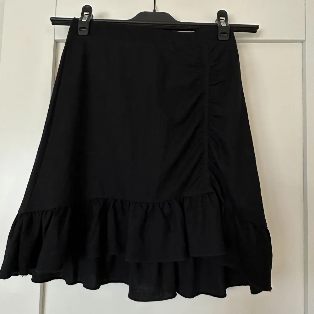 svart kjol med scrunch detalj och volanger, sitter relativt tajt. Kjolar.
