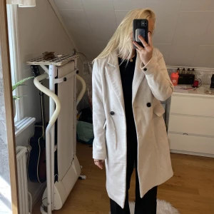 Kappa - En ljusbeige kappa ifrån Vero Moda. Är 160cm lång. Passar till höst/vinter då den är rätt så tjock. På insidan har sömmen spruckit på två ställen, som man kan rätt enkelt sy ihop.