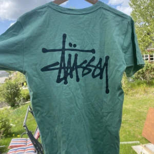 Stussy Tshirt - Stussy tshirt med snygg print och baksida. Har tyvärr blekning / färgfläck i högra armhålan men kan ses som ett rework/  syprojekt. Passar kvinna storlek Small