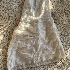 Krämvit klänning från H&M i linne-material med knytning i ryggen och fransar med pärlor nedtill 