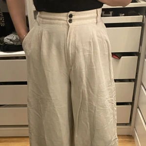 Croppade ”linnebyxor” - Croppade, utsvängda byxor i linnekänsla från H&M i färgen beige. Storlek 40 men skulle säga att den är mer en 38 i midjan.  Plagget finns i Ursvik, Sundbyberg om du önskar hämta det.
