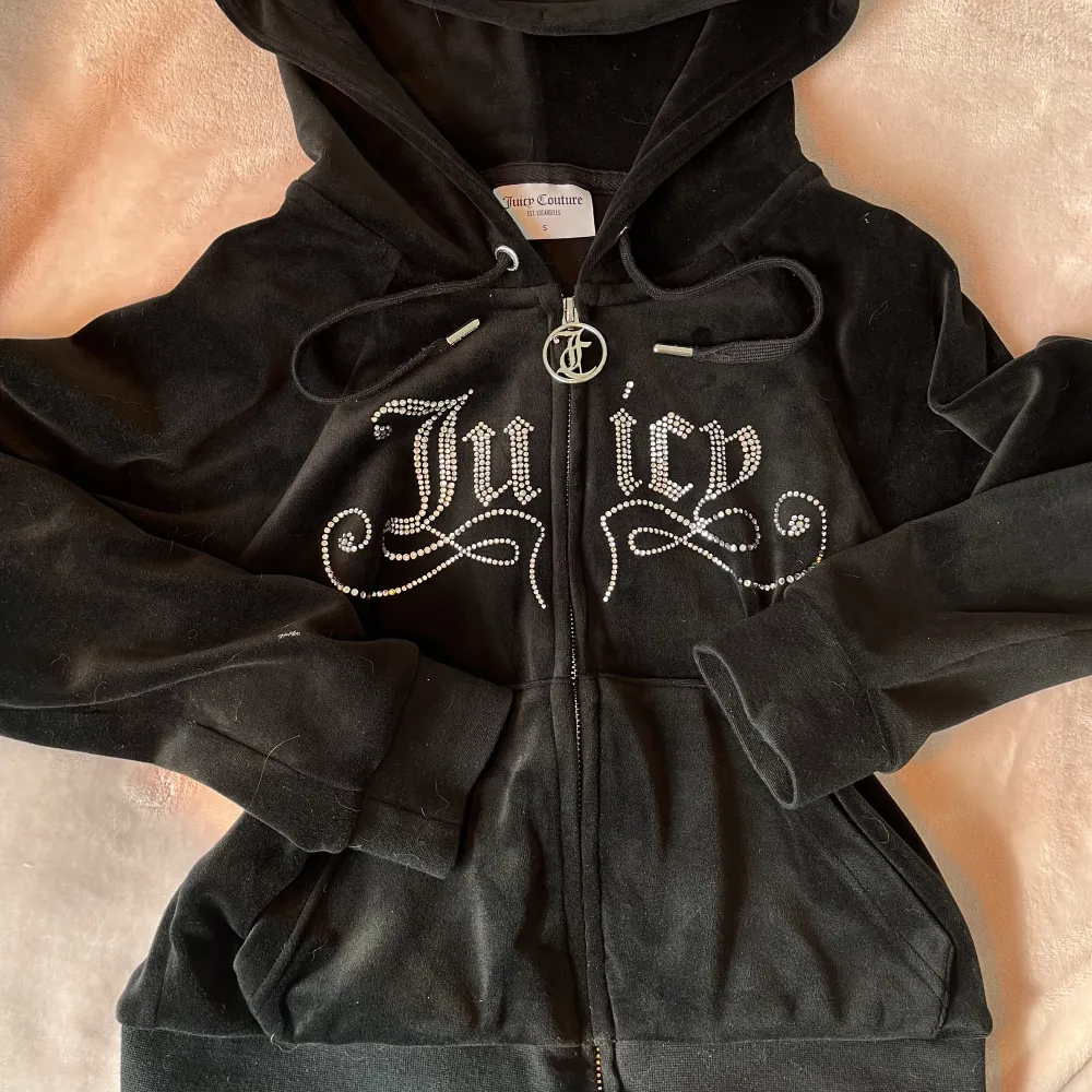 Juicy Couture svart Y2K rhinestone zip up hoodie med alla rhinestones kvar. Köpt för ca 2 år sedan på Urban Outfittets. Säljer då jag endast använt 2 gånger. Nypris 1077kr (€95). Vad jag hittat är de. slutsåld överallt 💕Supermjuk i tyget. Hoodies.