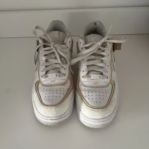 Air force 1 shadow - Ett par air force 1 shadow i ljus färg, använda men inga direkta skador eller särskilt nedslitna. Några få skrapor på skinnet bara.  Köpte för 1400 kr