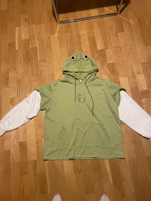 Frog hoodie - En gullig hoodie med en broderad groda på! Den är i nyskick och är väldigt skön. Storleken är large men jag på bilden har storlek M i vanliga fall. Funkar också som S om man vill ha den oversized!