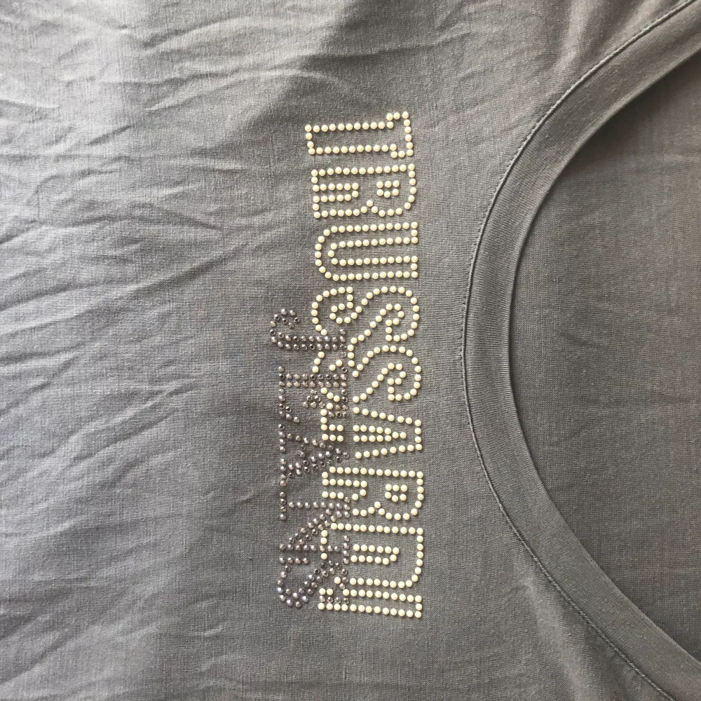 Grå baby-tee/ t shirt från Trussardi jeans med pärl text. Perfekt skick, köpt i Köpenhamn. . T-shirts.