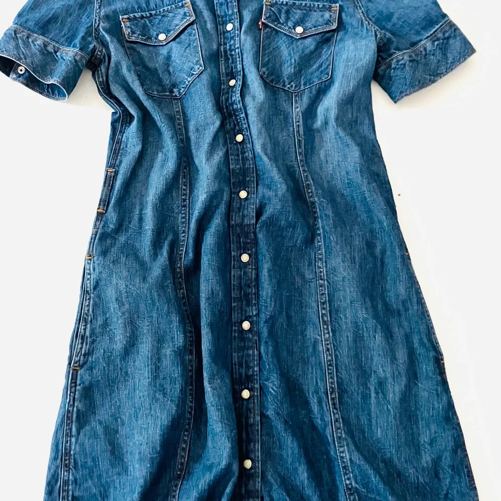 Klassisk jeansklänning med stel krage, tryckknappar, detaljresår bak samt möjlighet till skärp/utan skärp. Passar som sommarklänning alt med stövlar på vinter.  Nypri 1599kr. Klänningar.