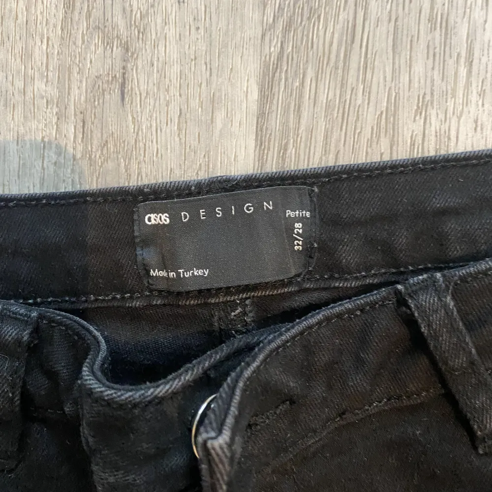 Svarta jeans från asos i storlek 32/28 petite . Jeansen har slits längst ner på bena och är använd ett fåtal gånger. . Jeans & Byxor.