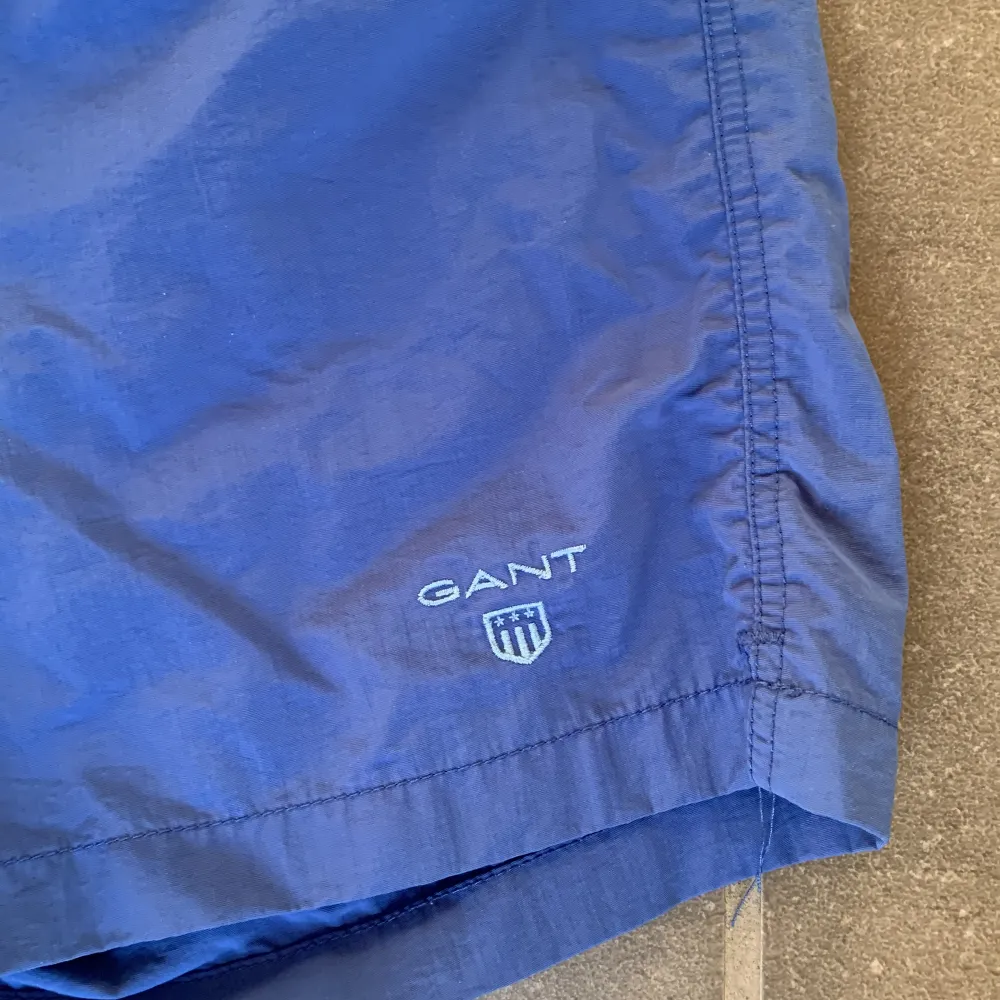 Ett par blå snygga Gant badbyxor som jag säljer för dom har blivit för små för mig. Det är en liten ”repa” på baksidan som knappt syns. Det finns 2 framfickor och en bakficka. Shorts.