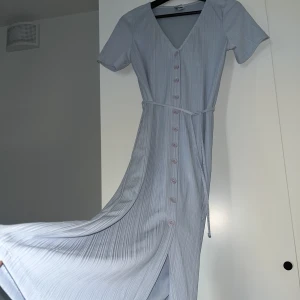 Ljusblå klänning - Ljusblå sommar klänning i svalt material, till halva smalbenen ungefär i längd. Knappar hela vägen och smal snörning i midjan 🦋