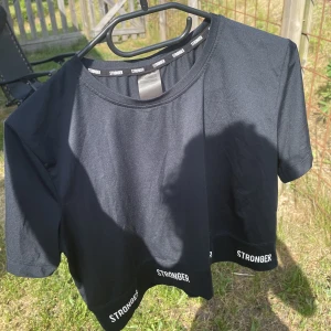 Träningströja  - Epic cropped tee från stronger i färgen mörkblå. Den är i ett väldigt skönt och luftande material. Använts ett par gånger men är i ett fint skick! Skickar gärna fler bilder så det är bara att höra av sig. Pris går att diskutera. 