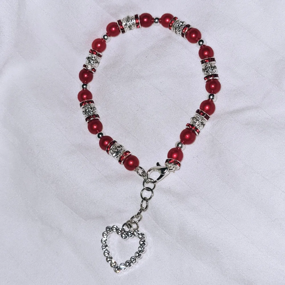 Röda akrylpärlor med silvriga pärlor i glitter med röda diamanter (ej äkta) tillsammans med charm. . Accessoarer.