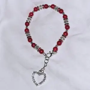Röda akrylpärlor med silvriga pärlor i glitter med röda diamanter (ej äkta) tillsammans med charm. 