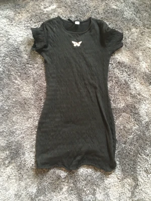 Svart sommar klänning  - En jättesöt klänning med en rosa fjäril på. Är i använt skick men har inga fläckar eller tydliga defekter. Strl M men passar mig som har Xs/s. OBS de svarta fläckarna är på spegeln. Vid intresse kontakta mig. Plagget tvättas innan postning. 