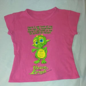 Baby Tee med Nessie the Dragon - T-shirt med Nessie the Dragon. Ingen storleksmärkning men passar XS och S.  Gott skick, aldrig använd.