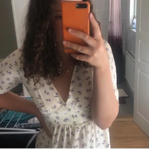 Blommig klänning - Blommig klänning med små volanger på ärmarna och smock i midjan och slits. 