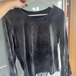 Grå långärmad med detaljer  - Grå långärmad tröja med detaljer framtill, utsvängda armar, köpt second hand