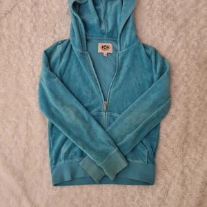 Juicy Couture Tröja  - Turkos blå Juicy Couture tröja, med gamla dragkedjan. Tröjan är i bra men i andvänt skick. Den har inga större brister förutom en liten fläck på sidan av luvan ( se bild 3). Lägg i åtanke att denna är köpt i affär ungefär runt 2014 - 2016!! 💕
