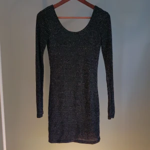 Klänning - Snygg festklänning med långärm som slutar över knäna. Svartglittrig i stretchtyg med en tunn svart underklänning som gör att det inte är stickit eller kliar. En skön och snygg klänning. 