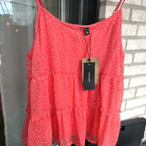 Blus, Linne - Säljer en blus med volang imitation. Blusen är korall och vit.  Blusen är aldrig använd, har prislapp kvar och är ny.  Färg: Korall Storlek: M