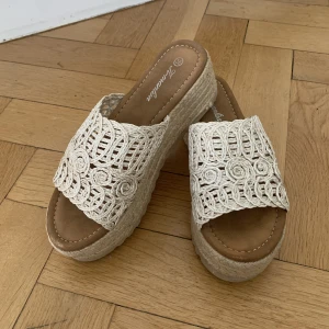 Beiga Tofflor  - Beiga broderade sommar tofflor, köpta i en liten butik i Marbella. Endast använda 1 gång, så i nyskick. Perfekta att ha till stranden eller på middag till linnebyxor eller en sommarklänning. 