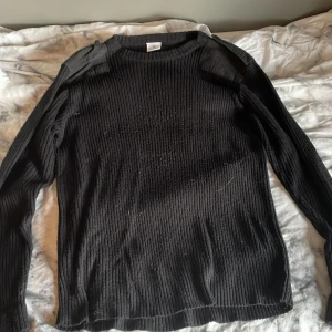 Svart stickad tröja - Jag säljer denna svart fina stickade tröjan med axellappar med axelklaffar och armbågs lappar. Använd ett fåtal gånger och är därför i ganska bra skick.