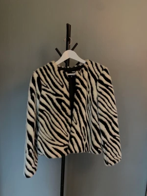 Zebrarandig jacka i fuskpäls, H&M - Zebrarandig jacka i fuskpäls från H&M. Rymlig 36:a.