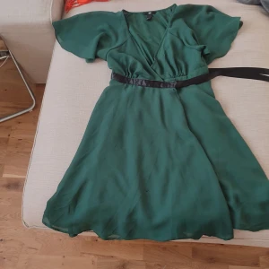 Klänning - Mörkgrön klänning i stl 38. Öppnas fram och stängs med knapp och snöre  Katt finns i hemmet
